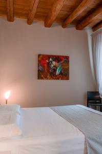 a bedroom with a white bed and a painting on the wall at Torre Soave - Locazione Turistica in Soave