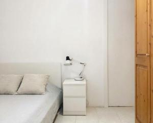 a white bedroom with a bed and a lamp on a night stand at Rooms in Palma Center in Palma de Mallorca