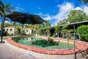 uma piscina com um guarda-sol num quintal em Tasman Holiday Parks - Hervey Bay em Hervey Bay
