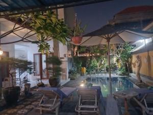 a swimming pool with chairs and an umbrella at Sanata Yoga Guesthouse in Canggu