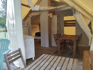 a room with a table and chairs and a kitchen at Camping du pont d'Oust in Peillac +4 photos