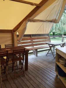 a wooden porch with a wooden table and benches at Camping du pont d'Oust in Peillac