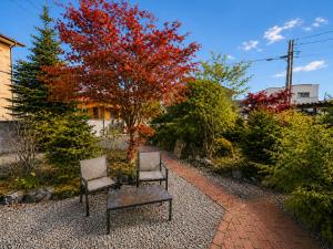 two chairs sitting in front of a tree with red leaves at House Villa Koharu in Asahikawa