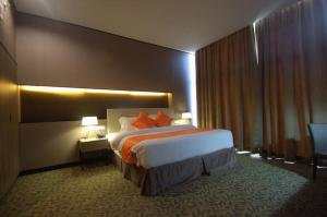 فندق غراند ألورا في ألور سيتار: غرفة فندق بسرير ومخدات برتقال
