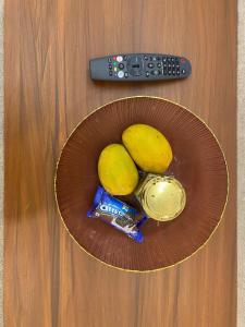 a bowl with two lemons and a bag of chips and a remote control at KD Homes - Elite studio stay in Surat +20 photos