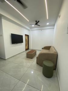 a living room with a couch and a tv on a wall at KD Homes - Elite studio stay in Surat