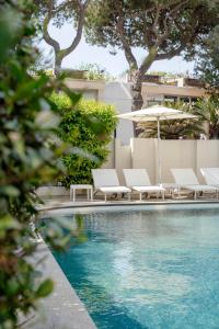 a swimming pool with white chairs and an umbrella at Hotel Ambasciatori in Rimini