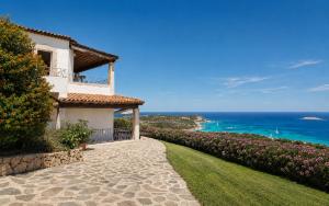 a house with a pathway leading to the ocean at Big Pevero Sea View House 7 Two Bedrooms in Porto Cervo