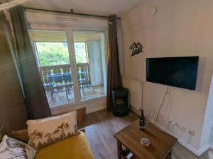 a living room with a couch and a flat screen tv at Cauterets Mountain Nest in Cauterets