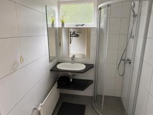 a small bathroom with a sink and a shower at De Duinrand in Oostkapelle +19 photos