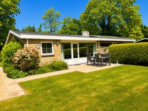 a brick house with a patio and a lawn at De Duinrand in Oostkapelle