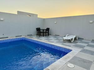 a swimming pool in a room with a table and chairs at Al Safwa One in Al Ḩadd
