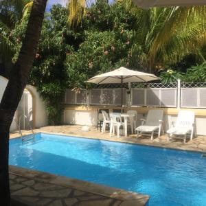 a swimming pool with chairs and an umbrella at Rayan Tourist Villa in Flic-en-Flac