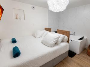 a white bedroom with a white bed with blue pillows at La Cave Des Merveilles in Mâcon