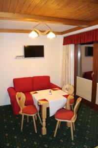 ein Wohnzimmer mit einem roten Sofa, einem Tisch und Stühlen in der Unterkunft Apartments at Berghaus Glockner in Heiligenblut