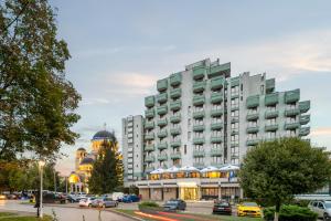 a large building in a city with a parking lot at Hotel Sarmis in Deva