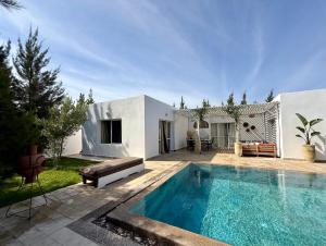 a swimming pool in front of a white house at Villa TerraVerde in Al Ghar +14 photos
