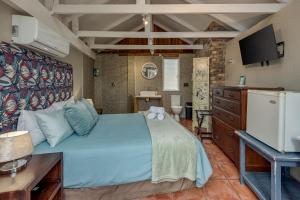 a bedroom with a blue bed and a tv at Mill Park Corner Cottages in Port Elizabeth