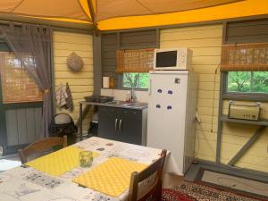 a kitchen with a table and a white refrigerator at The Yurt at Les Forges in Saint-Sornin-la-Marche