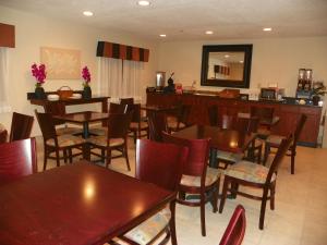 un restaurant avec des tables, des chaises et un miroir dans l'établissement Royalton Inn & Suites Upper Sandusky, à Upper Sandusky