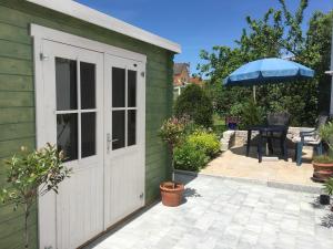 a shed with a white door and a table with an umbrella at Ferien-Apartment Beller in Strullendorf