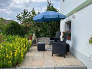 a patio with a blue umbrella and chairs and flowers at Ferien-Apartment Beller in Strullendorf +61 photos