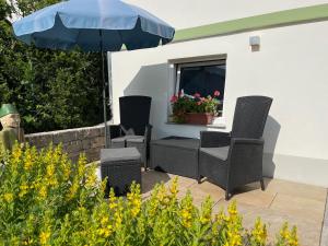 a patio with three chairs and an umbrella at Ferien-Apartment Beller in Strullendorf