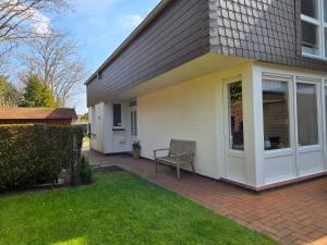 a house with a porch with a chair on a patio at Nr 64 - Ferienhaus Krabbe 12 in Carolinensiel