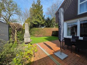 a patio with a table and a monument in front of a house at Nr 64 - Ferienhaus Krabbe 12 in Carolinensiel
