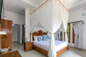 a bedroom with a canopy bed with white curtains at Villa Aniela Legian in Legian +34 photos