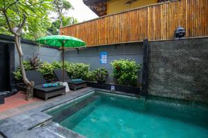 a swimming pool with an umbrella next to a building at Villa Aniela Legian in Legian