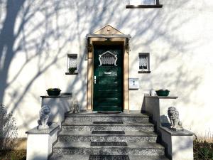 a green door on a white building with stairs at Villa Seenswert in Lauta