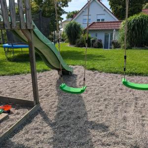a playground with two swings and a slide at Ferienhaus Frieda mit 2 Schlafzimmern in Sagard