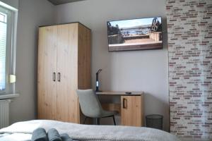 a bedroom with a bed and a cabinet and a desk at Ferienwohnung "ZU HAUSE" in Guben