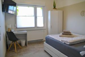 a bedroom with a bed and a desk and a refrigerator at Ferienwohnung "ZU HAUSE" in Guben +12 photos