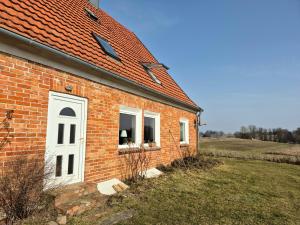 a brick building with a white door and a window at Ferienwohnung Kranichblick in Hoppenrade
