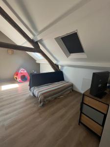 a attic room with a bed and a flat screen tv at Chez Paulette - par Happy House in Gouzon