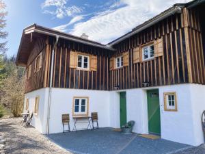 a house with a green door and chairs at Mitteralm-Kreuth in Kreuth