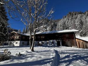 a snow covered building with a tree in front of it at Mitteralm-Kreuth in Kreuth