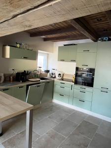 a kitchen with green cabinets and a table in it at Chez Paulette - par Happy House in Gouzon
