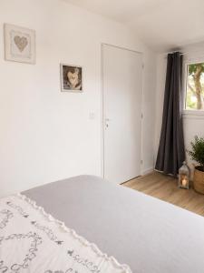 a white bedroom with a bed and a window at Chambre Cocon, bienvenue chez Sylviane in Marennes
