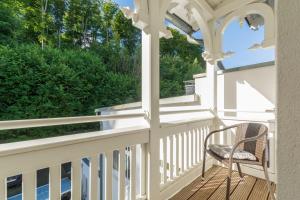 a rocking chair on a porch with a view of trees at Villa Eden II in Binz