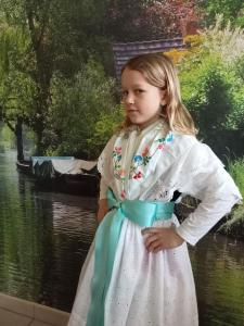 a little girl in a dress standing in front of a painting at Spreewald-Pension Marina in Lübben