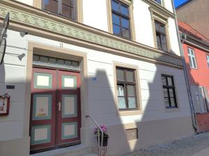 a white building with a red door on a street at Altstadthaus Stralsund Külpstraße 11 in Stralsund