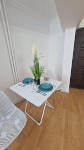 a white table with two plates and a plant on it at Gabriela Studio in Drobeta-Turnu Severin