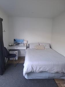 a bedroom with a white bed and a desk at TuiHideaway cozy studio sleepout in Mount Maunganui