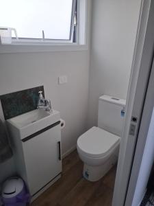 a bathroom with a toilet and a sink and a window at TuiHideaway cozy studio sleepout in Mount Maunganui +9 photos