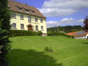 ein großes Gebäude auf einem grasbewachsenen Hügel vor einem Haus in der Unterkunft Gästehaus St. Michael in Mossautal