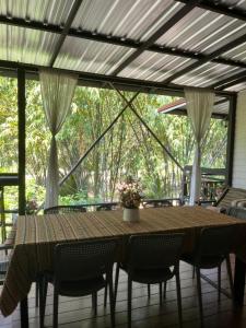 a wooden table and chairs on a screened porch at บ้านชมธาร บ้านสวนสราญชล in Ban Plai Nam (2)
