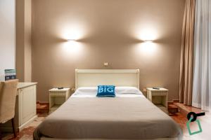 a bedroom with a bed with a blue pillow on it at Hotiday Porto Cesareo Spiaggia in Porto Cesareo